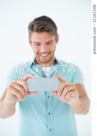 Happy young man looking at his mobile phone 12161306