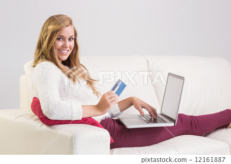 Pretty blonde relaxing on sofa with laptop 12161887