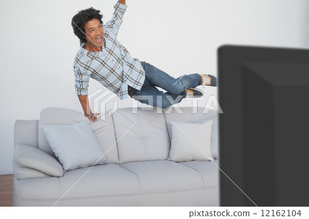 Happy soccer fan cheering while watching tv Happy soccer fan cheering while watching tv 12162104