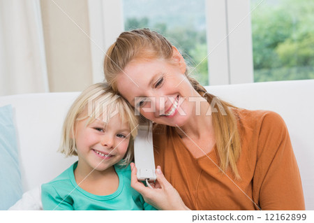Happy mother and daughter on the couch on the phone 12162899