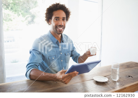 Casual man having coffee while using tablet Casual man having coffee while using tablet 12162930