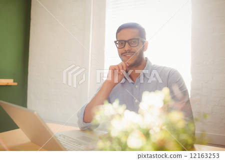 Casual businessman using his laptop at his desk 12163253