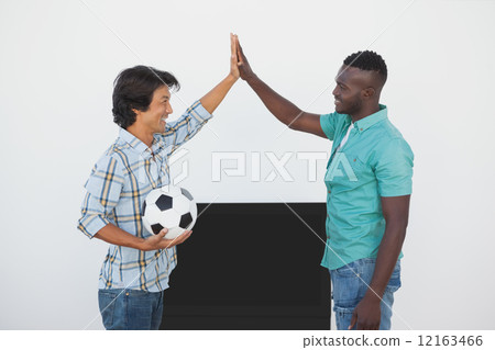 Soccer fans high fiving while watching tv 12163466