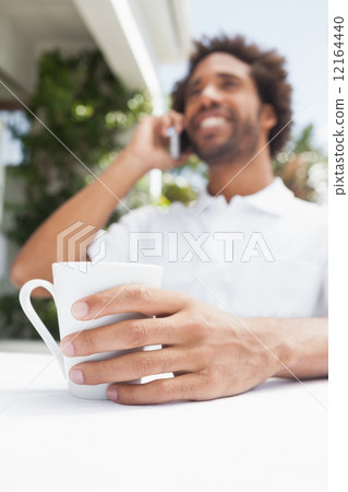 Smiling man on the phone having coffee 12164440