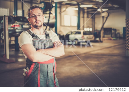 Serviceman in a car workshop 12176612