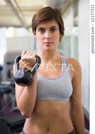 Fit brunette lifting kettlebell looking at camera Fit brunette lifting kettlebell looking at camera 12177312