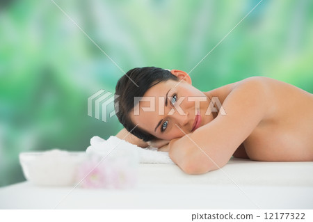 Beautiful brunette relaxing on massage table smiling at camera 12177322