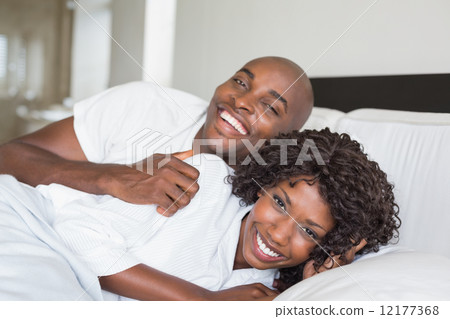 Happy couple lying in bed together 12177368