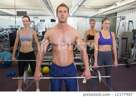 Fitness class lifting barbells together 12177487