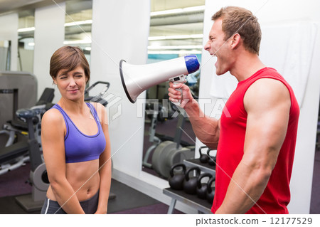Personal trainer shouting at client through megaphone 12177529
