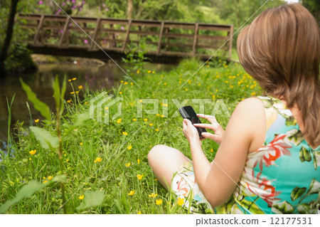 Woman text messaging in field 12177531