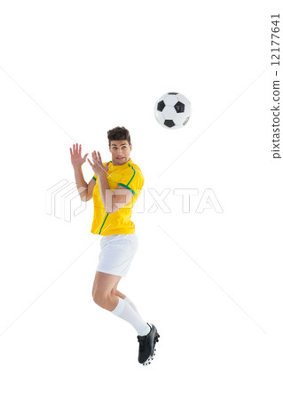 Football player in yellow jersey jumping to ball Football player in yellow jersey jumping to ball 12177641