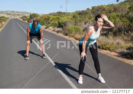 Athletic couple taking a break from jogging on the open road Athletic couple taking a break from jogging on the open road 12177717