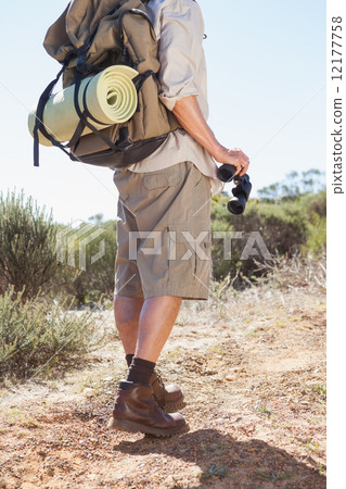 Hiker holding his binoculars on country trail Hiker holding his binoculars on country trail 12177758