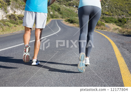 Fit couple running together down a road 12177804