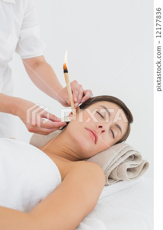 Beautiful woman receiving ear candle treatment at spa center 12177836