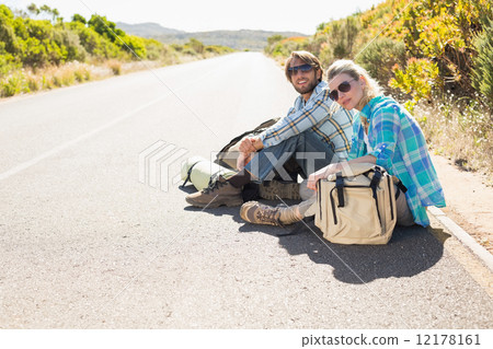 Attractive couple sitting on the road waiting for a lift Attractive couple sitting on the road waiting for a lift 12178161