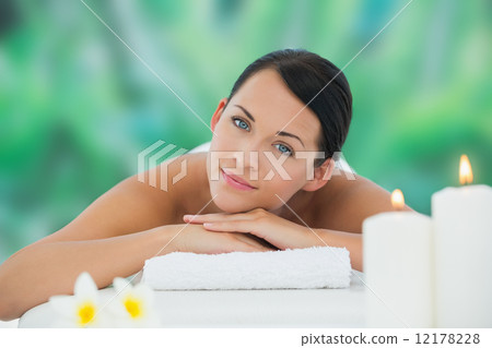 Beautiful brunette relaxing on massage table smiling at camera Beautiful brunette relaxing on massage table smiling at camera 12178228