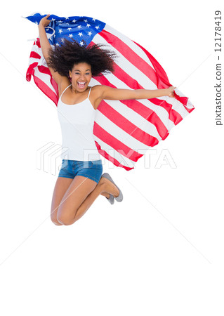 Pretty girl wrapped in american flag jumping and smiling at came Pretty girl wrapped in american flag jumping and smiling at came 12178419