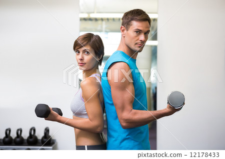 Fit couple lifting dumbbells together 12178433