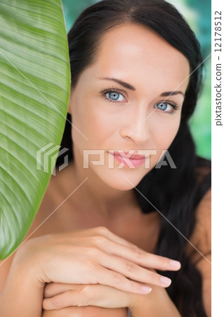 Beautiful nude brunette smiling at camera with green leaf 12178512