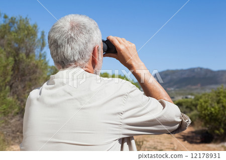 Hiker taking a break on country trail looking through binoculars 12178931