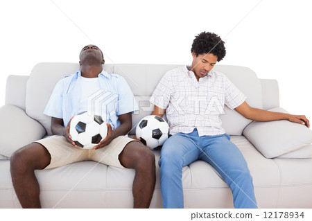 Distraught football fans sitting on the couch with balls Distraught football fans sitting on the couch with balls 12178934