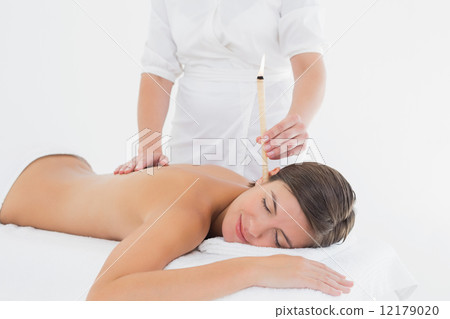 Beautiful woman receiving ear candle treatment at spa center Beautiful woman receiving ear candle treatment at spa center 12179020
