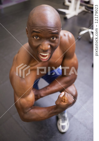 Muscular man shouting while flexing muscles 12179023