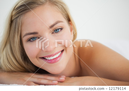 Beautiful blonde lying on massage table smiling at camera Beautiful blonde lying on massage table smiling at camera 12179114
