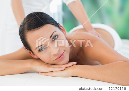 Beautiful brunette enjoying a back massage smiling at camera 12179136