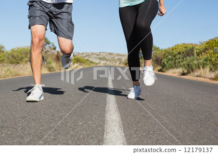 Fit couple running on the open road together 12179137