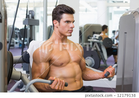 Determined muscular man working on abdominal machine 12179138