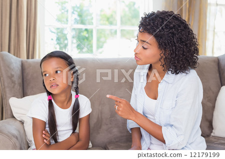 Pretty mother sitting on couch scolding her daughter 12179199