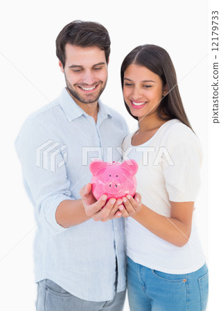 Happy couple holding their piggy bank Happy couple holding their piggy bank 12179733