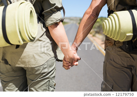 Hitch hiking couple standing holding hands on the road 12179750