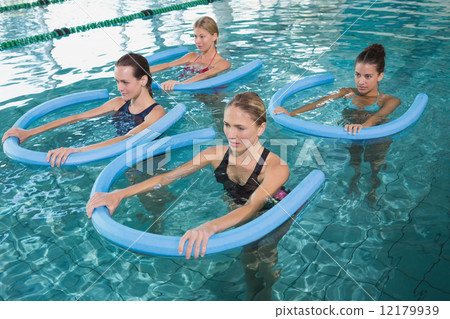 Fitness class doing aqua aerobics with foam rollers