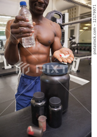 Shirtless muscular man holding vitamin pills 12179971