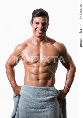 Portrait of a smiling shirtless muscular man wrapped in towel 12180059