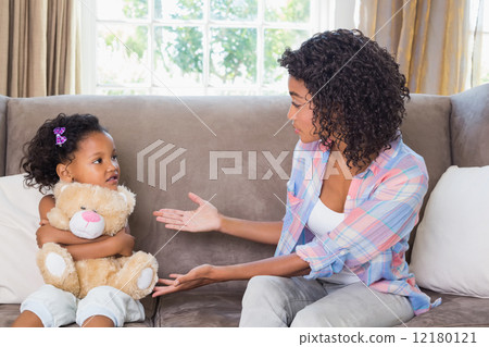 Pretty mother sitting on couch with petulant daughter 12180121