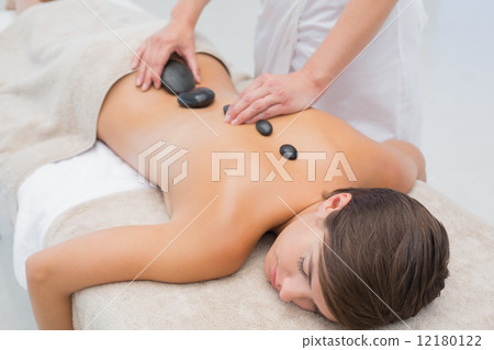 Beautiful woman receiving stone massage at spa center 12180122
