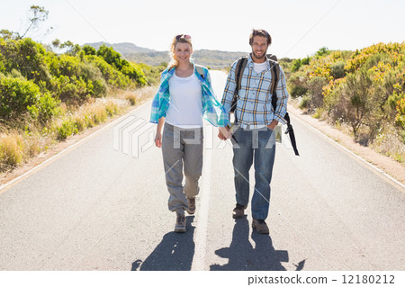 Attractive couple standing on the road holding hands smiling at Attractive couple standing on the road holding hands smiling at 12180212
