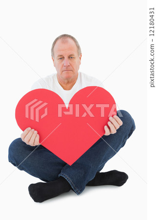 Upset man sitting holding heart shape Upset man sitting holding heart shape 12180431