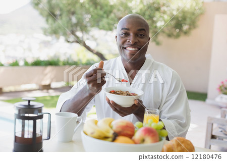 Handsome man in bathrobe having breakfast outside 12180476