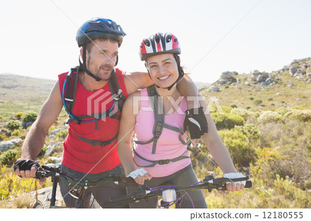 Fit cyclist couple smiling together on mountain trail 12180555
