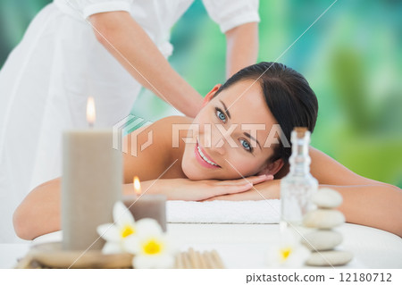 Beautiful brunette enjoying a back massage smiling at camera 12180712