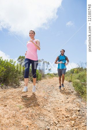 Fit attractive couple jogging down mountain trail 12180748