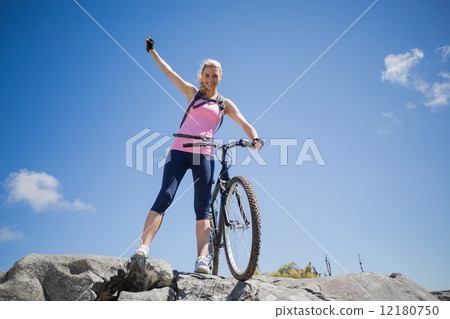 Fit pretty cyclist on a rocky terrain smiling at camera Fit pretty cyclist on a rocky terrain smiling at camera 12180750