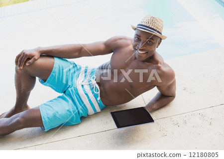 Handsome shirtless man using tablet pc poolside Handsome shirtless man using tablet pc poolside 12180805