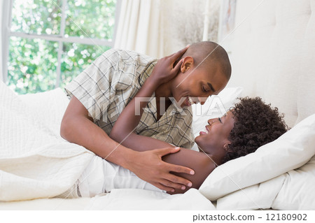Intimate couple cuddling lying on their bed 12180902